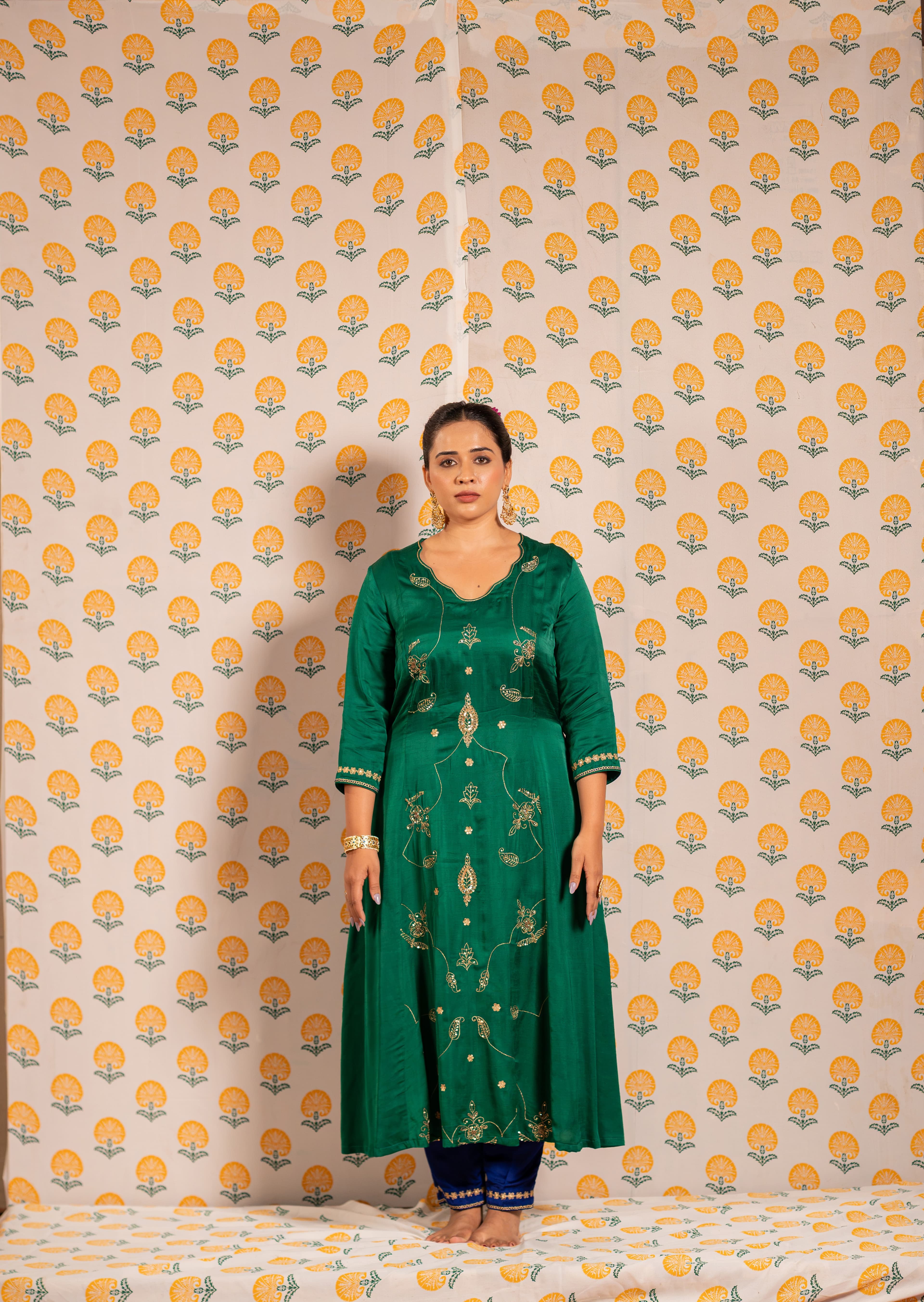 A rich green Aline kurta set with handwork paired with bluish-purple pant